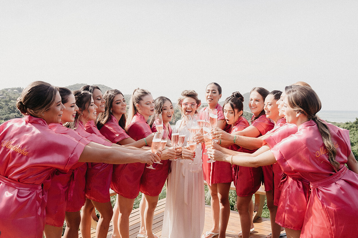 noiva e madrinhas com robe rosa brindando