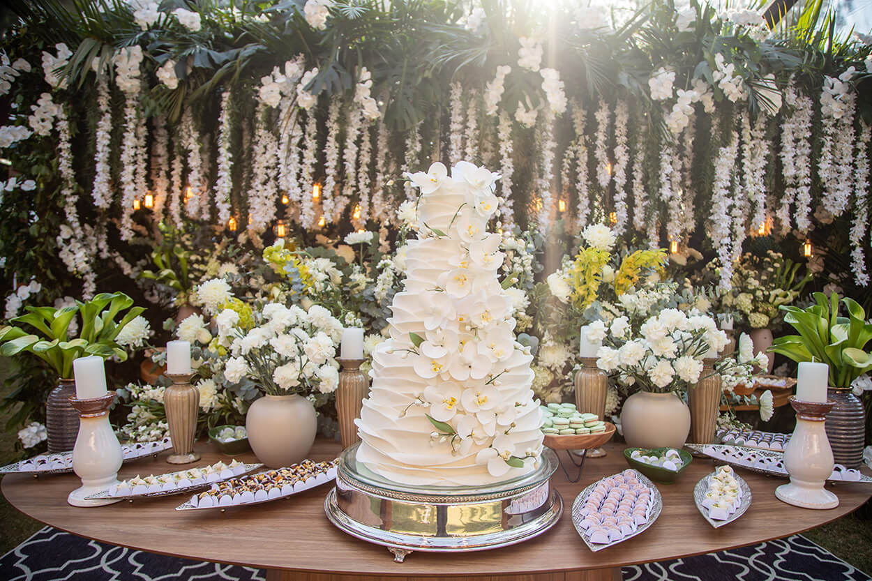 mesa com bolo com quatro andares e flores no topo