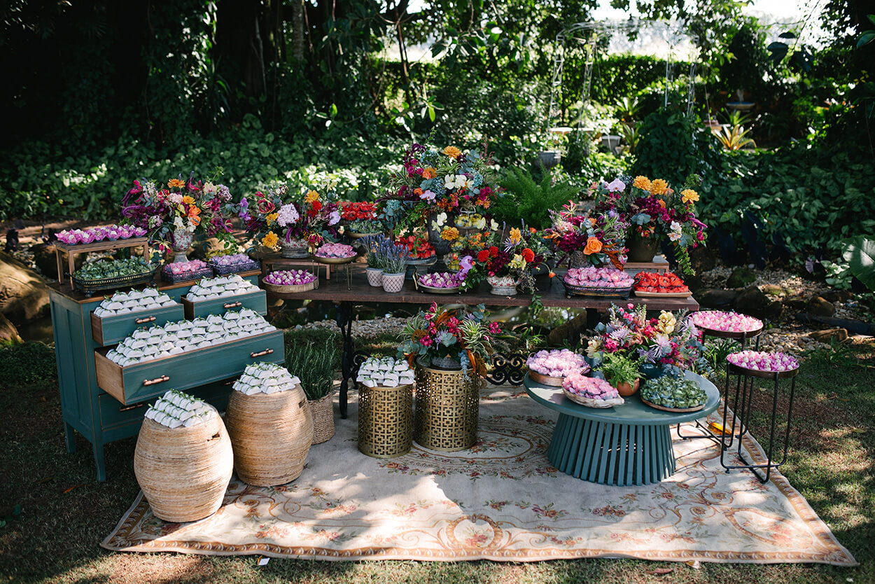 mesa com doces de casamento e arranjo com flores rosas laranjas e vermelhas