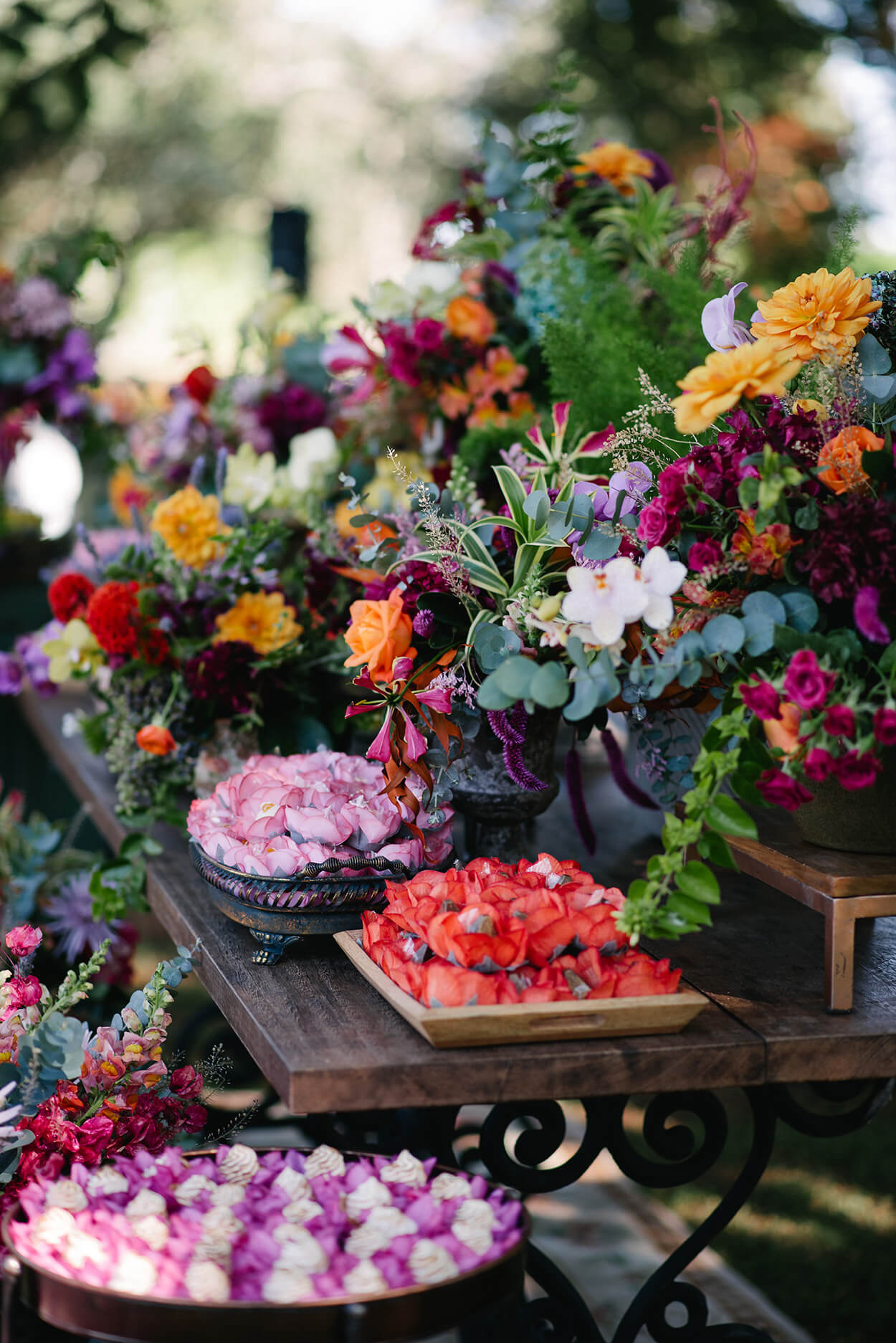 mesa com doces de casamento e arranjo com flores rosas laranjas e vermelhas