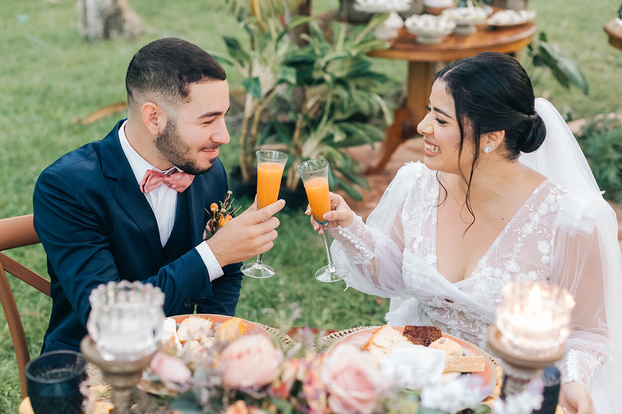 Noivos brindando em taça durante coquetel em casamento de tarde