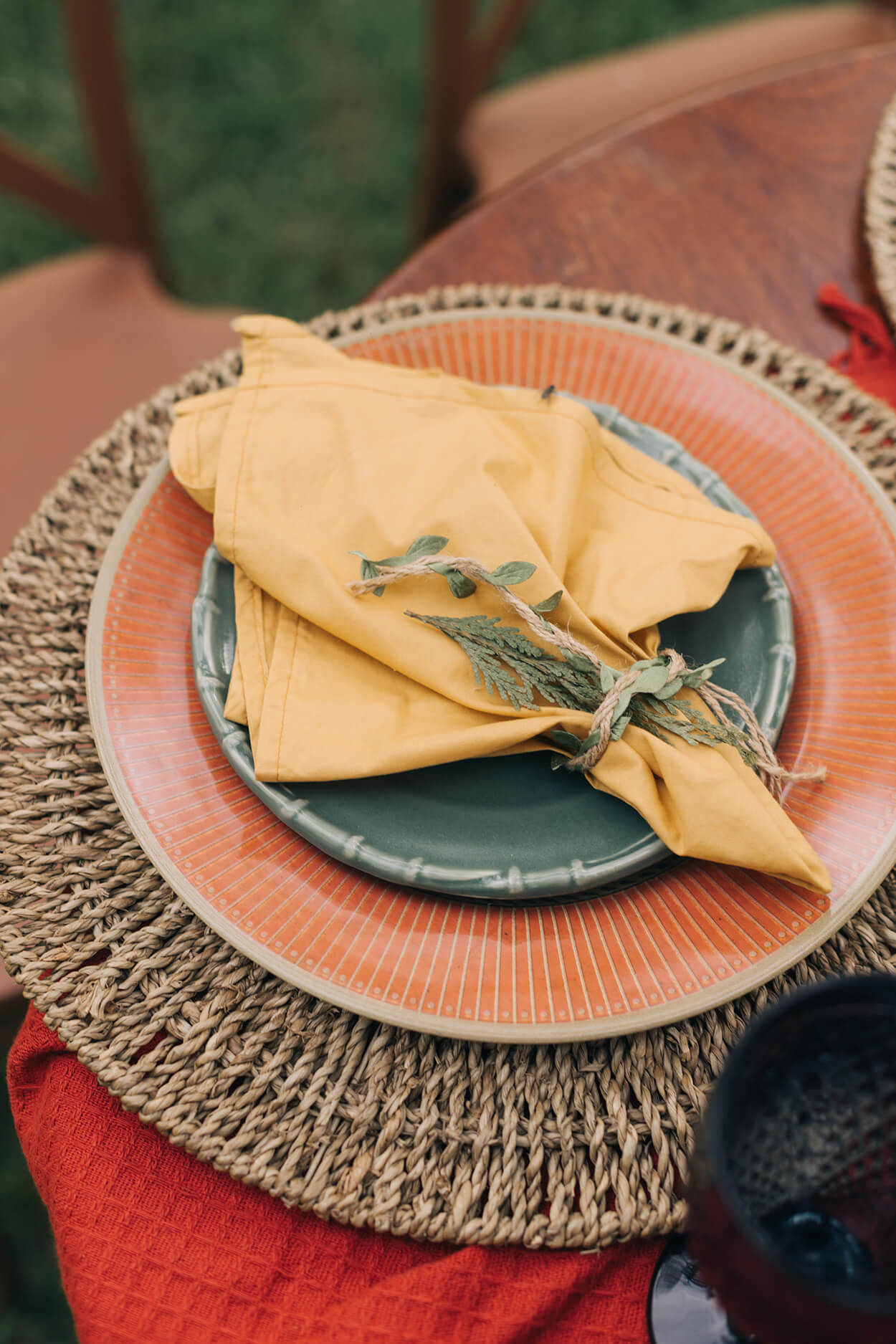 sousplat rústico com pratos laranja verde e guardanapo amarelo