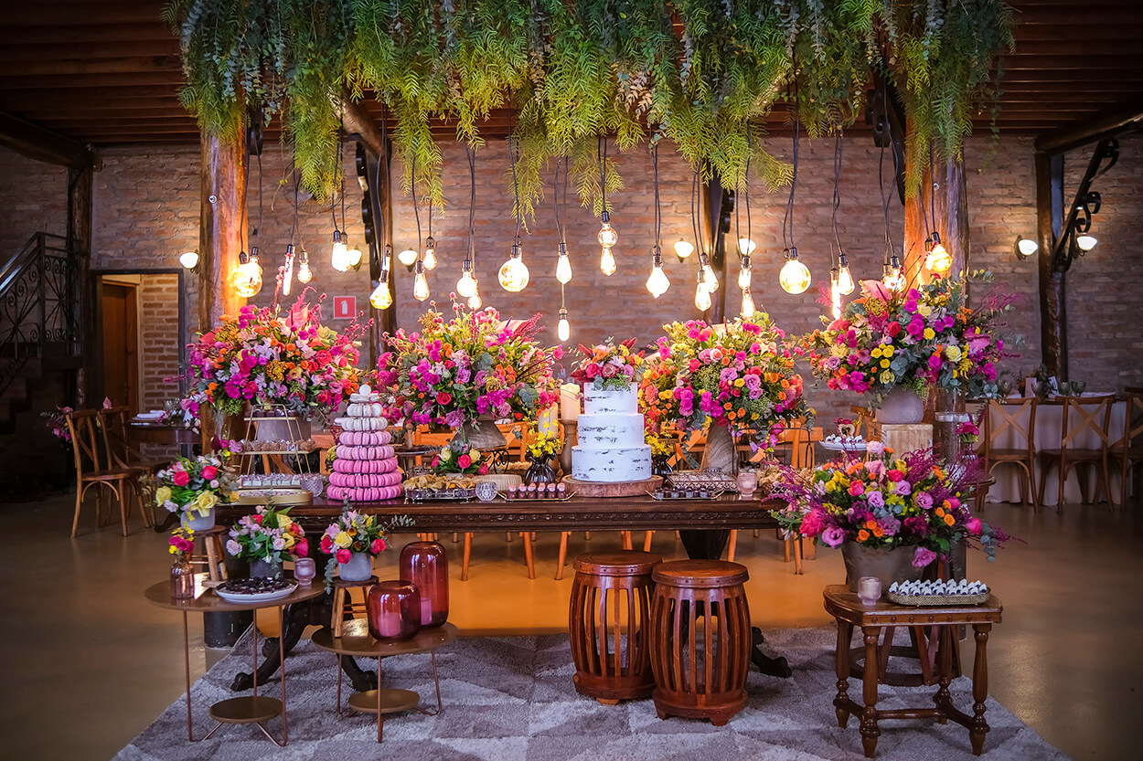 mesa do bolo com arranjos com flores rosas e laranjas