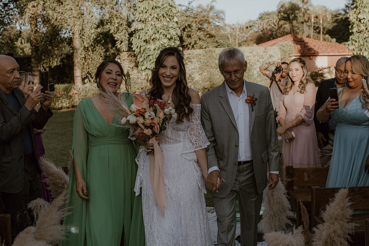 entrada da noiva com o pai com tenro cinza e mãe com vestido verde 