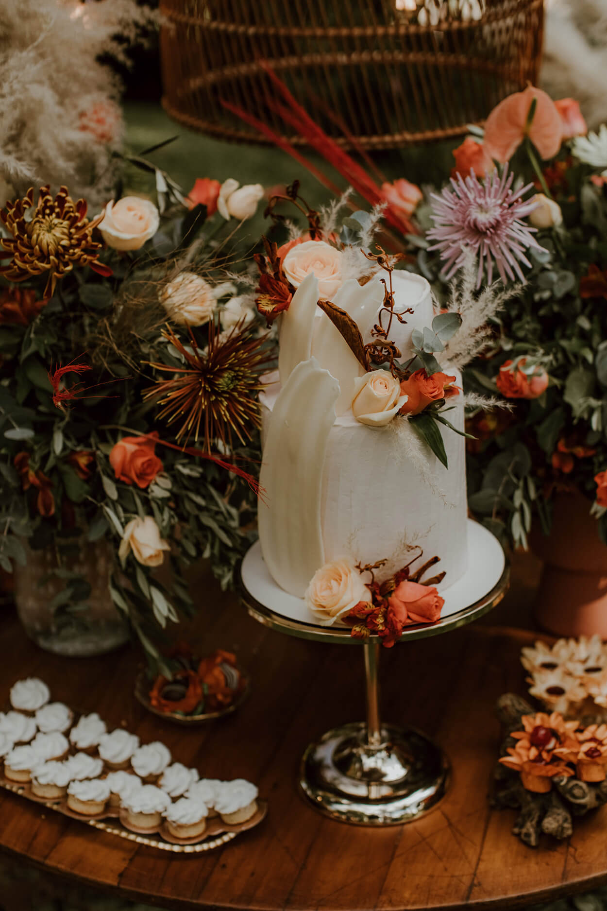 bolo de casamento branco com dois andares com rosas ao lado de vasos com flores