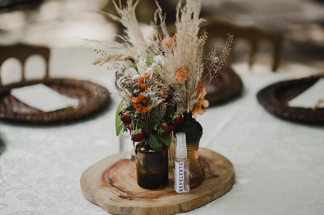 centro de mesa com bolacha de madeira e vaso marrom com morangos flores laranjas e capim dos pampas