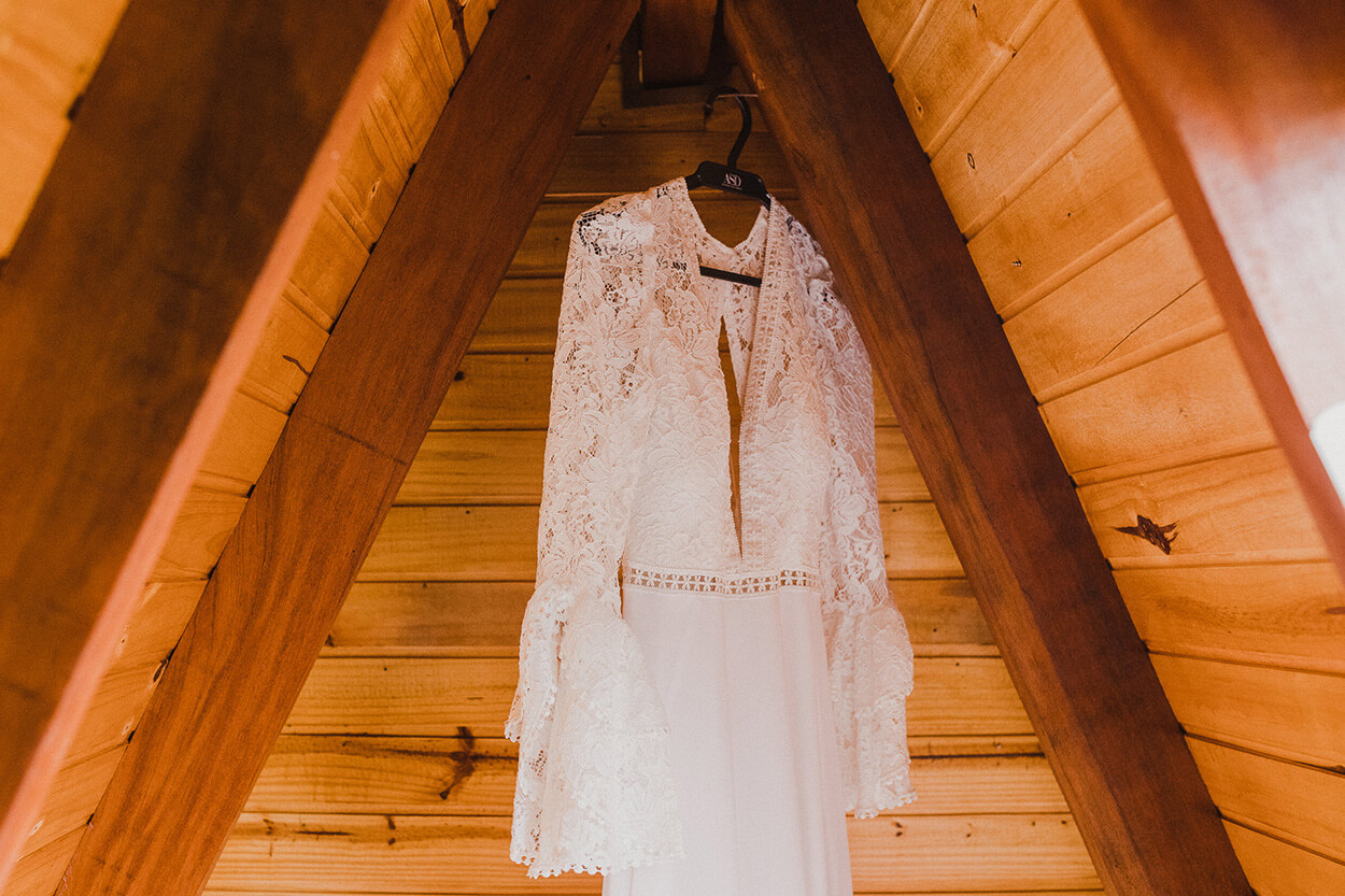 vestido de noiva com manga longa pendurado no cabide dentro do chalé