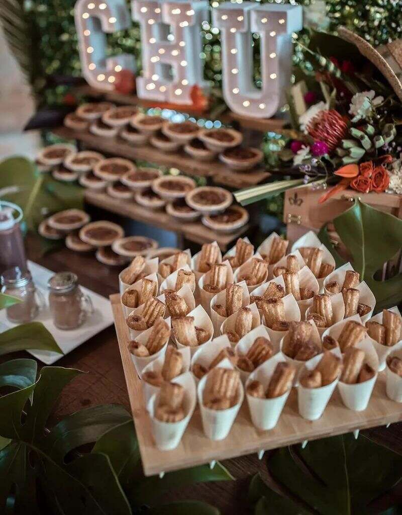mesa com mini churros para servir como doce de casamento em copinho
