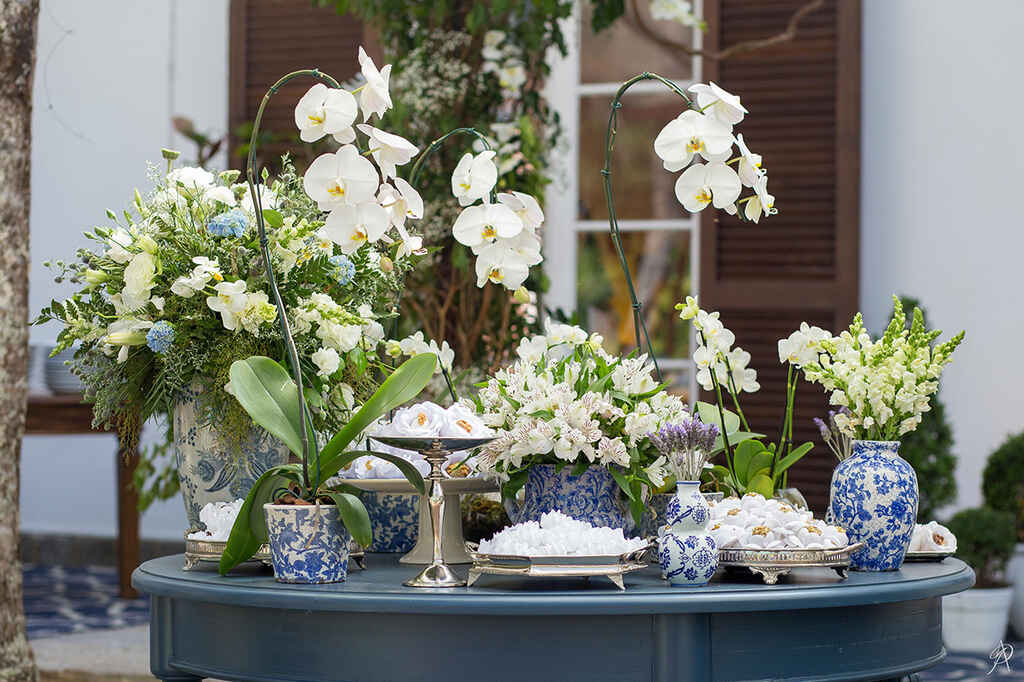 mesa azul com vasos com flores brancas e orquideas