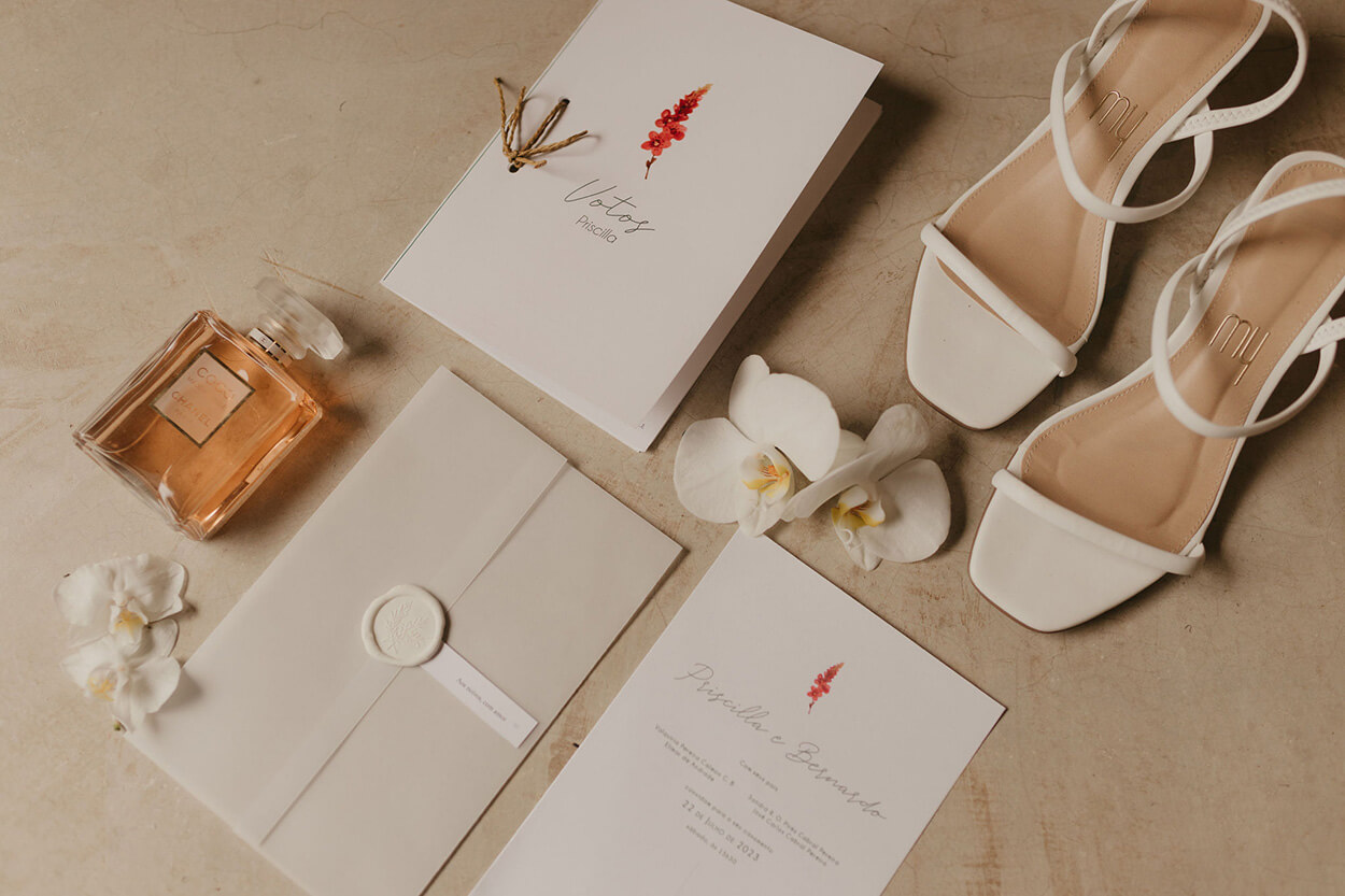 caderno de votos e convite de casamento branco ao lado ed perfume orquideas e sapato branco