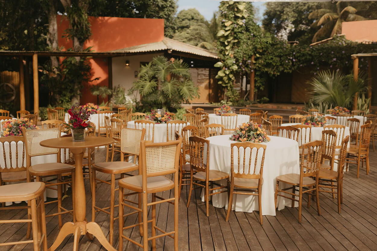 mesas redondas com toalhas brancas e flores amarelas e rosas no centro