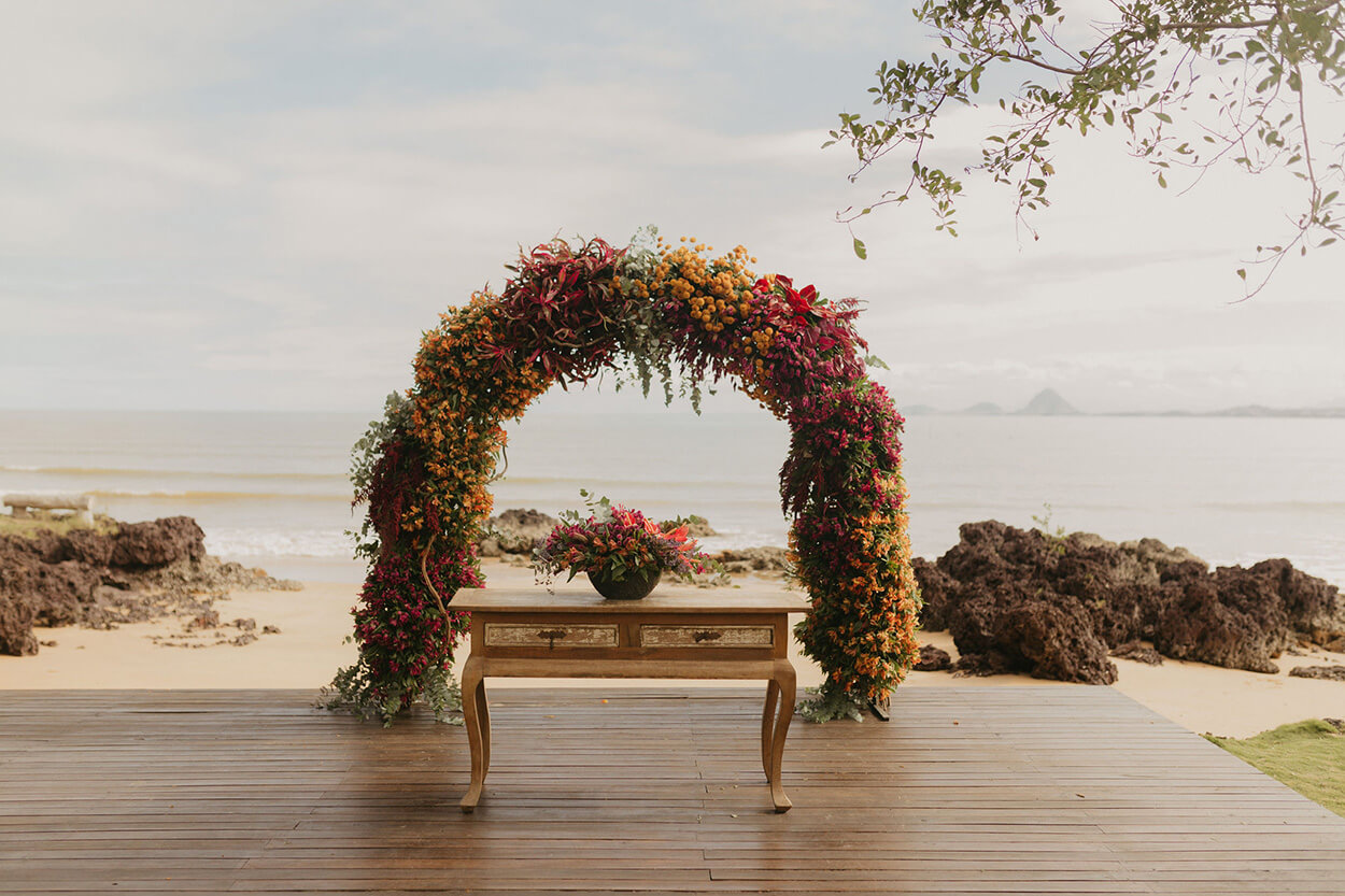 altar florido com flores amarelas laranjas e rosas de frente a areia da praia