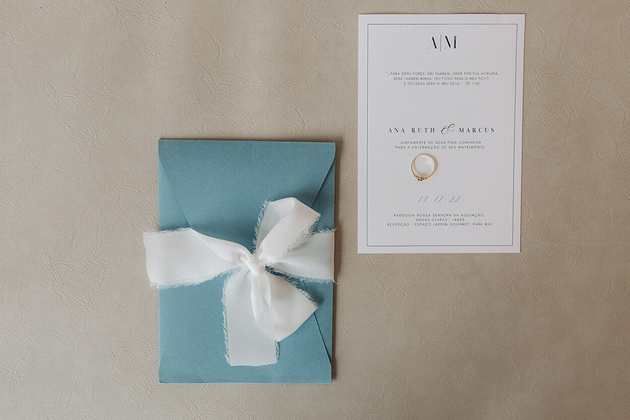 convite de casamento branco e envelope azul serenty ao lado com laço branco