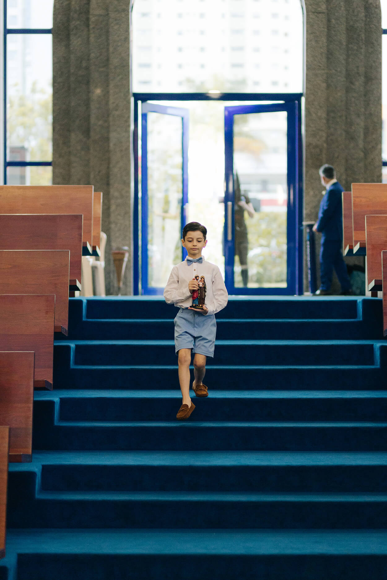 pajem levando estátua de santo enquanto desce as escadas da igreja