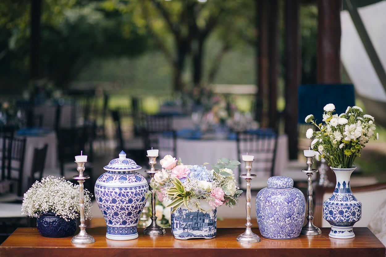 mesa de madeira com vasos brancos e azul e flores