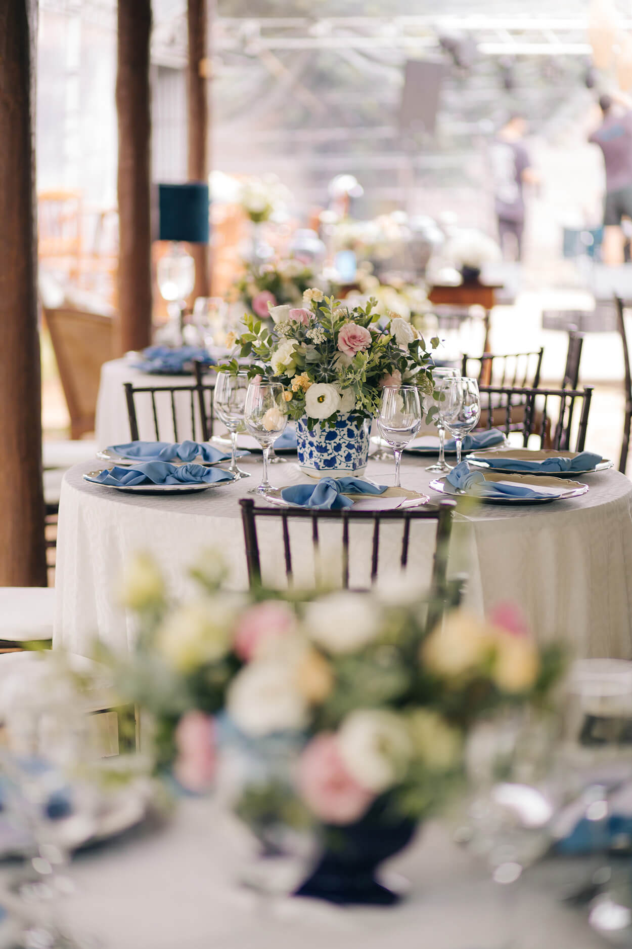 mesa redonda com toalha branca e mesa posta azul