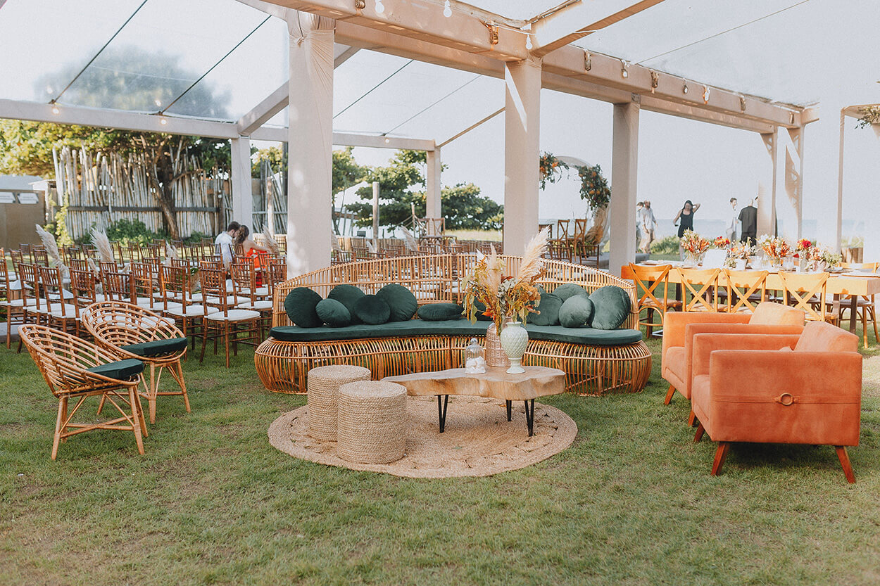 lounge ao ar livre com sofá verde e bambu e poltronas laranjas