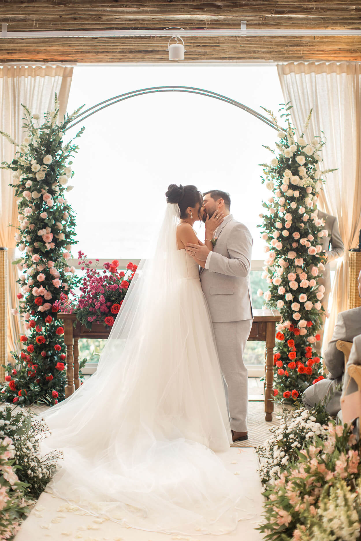 noivos se beijando no altar com flores brancas e rosas