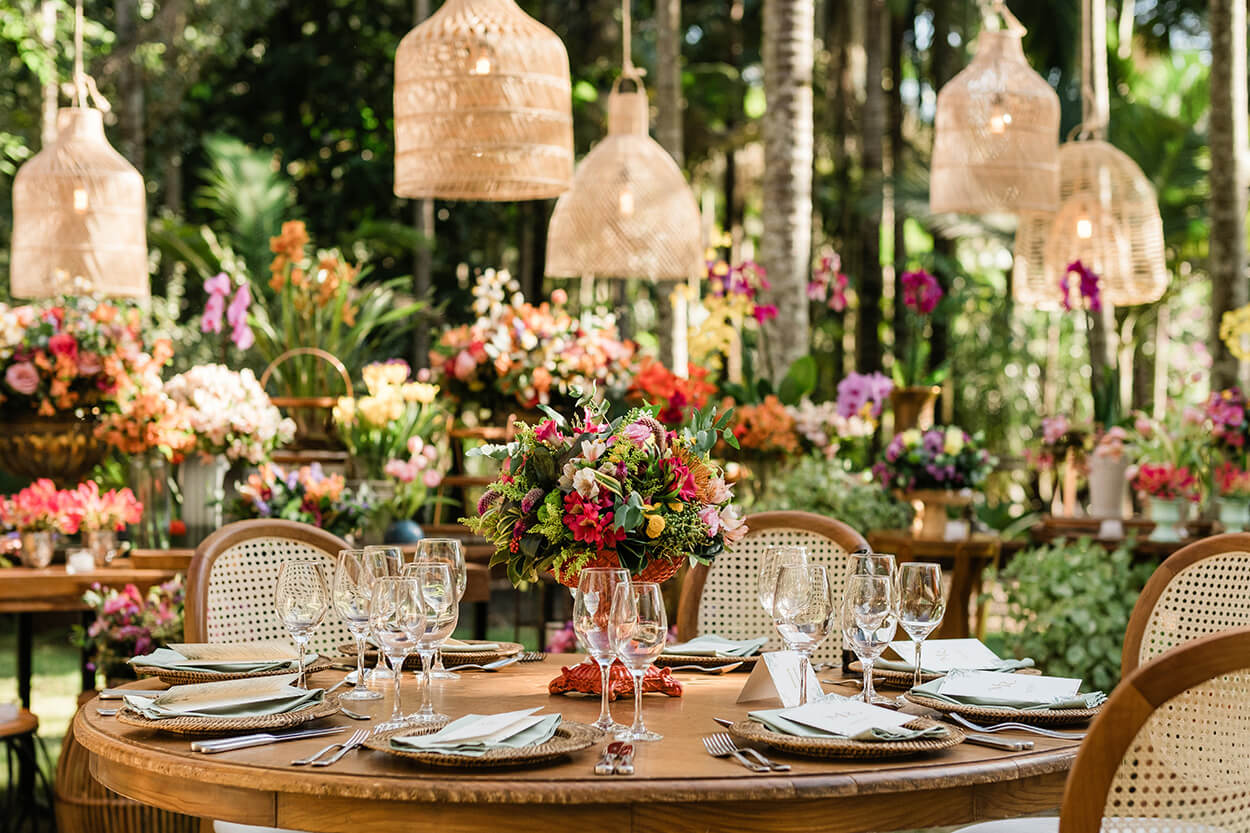 mesa posta redonda com vaso com flores coloridas no centro 