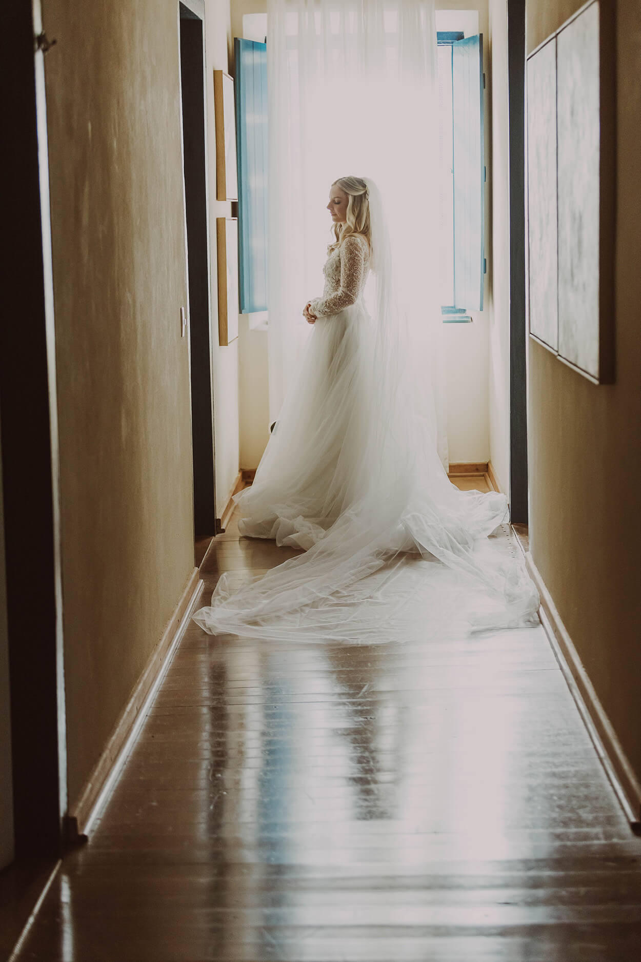 mulher com vestidos de noiva com cauda e véu longo no final do corredor