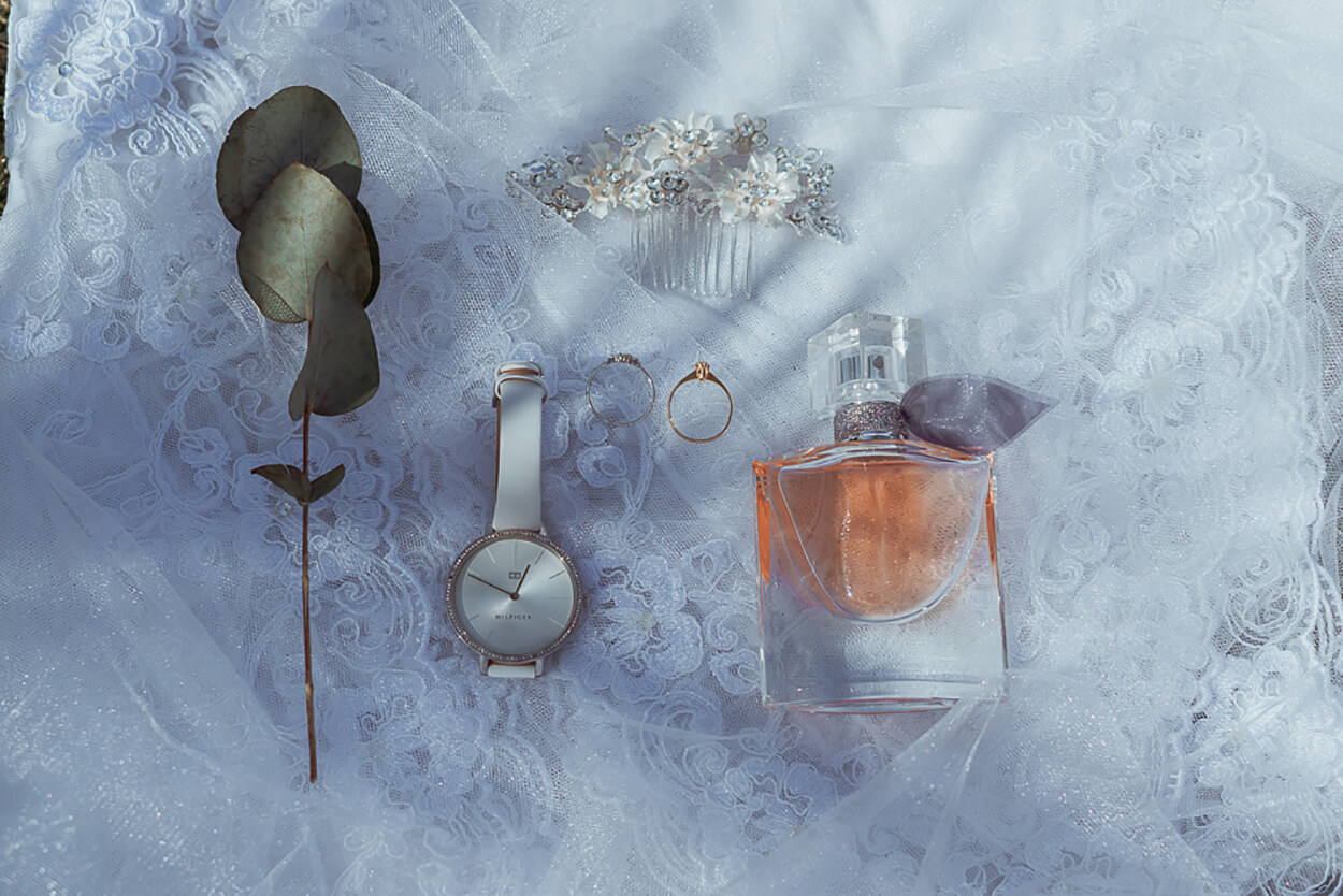 perfume com vidro laranja relogio feminino branco moderno aliança pente decorado com flores e ramo de folhas de eucalipto