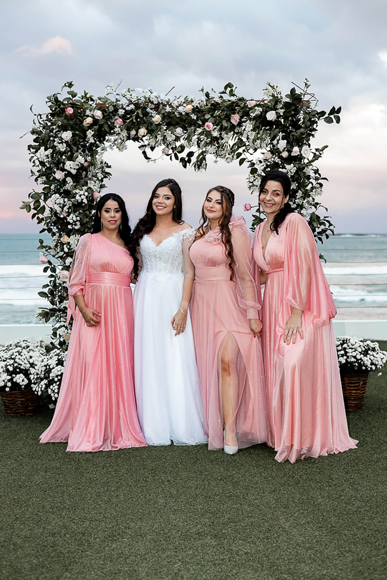 noiva ao lado de três mulheres com vestido longos e brilhangtes cor de rosa para madrinha