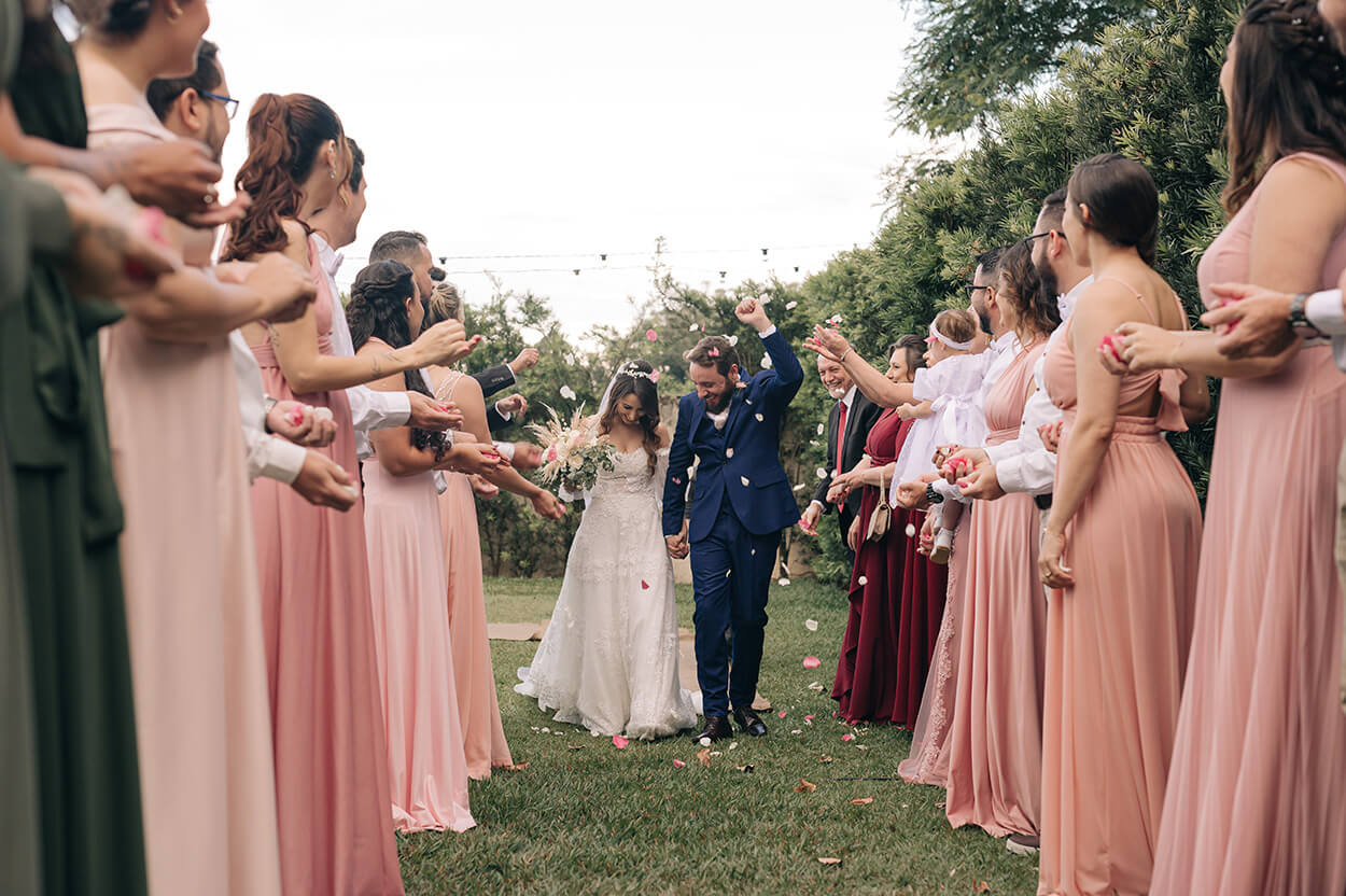 saída dos noivos e madrinhas com vestidos rosa jogando pétalas de flores