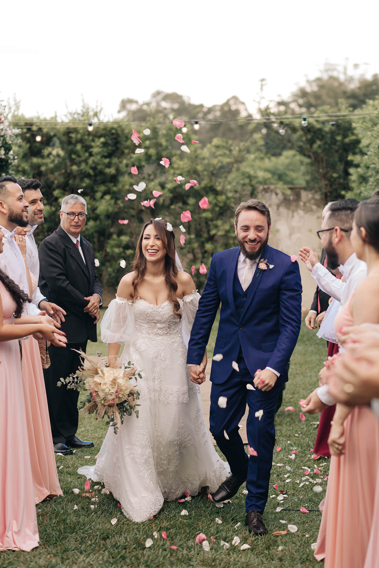 saída dos noivos e madrinhas com vestidos rosa jogando pétalas de flores
