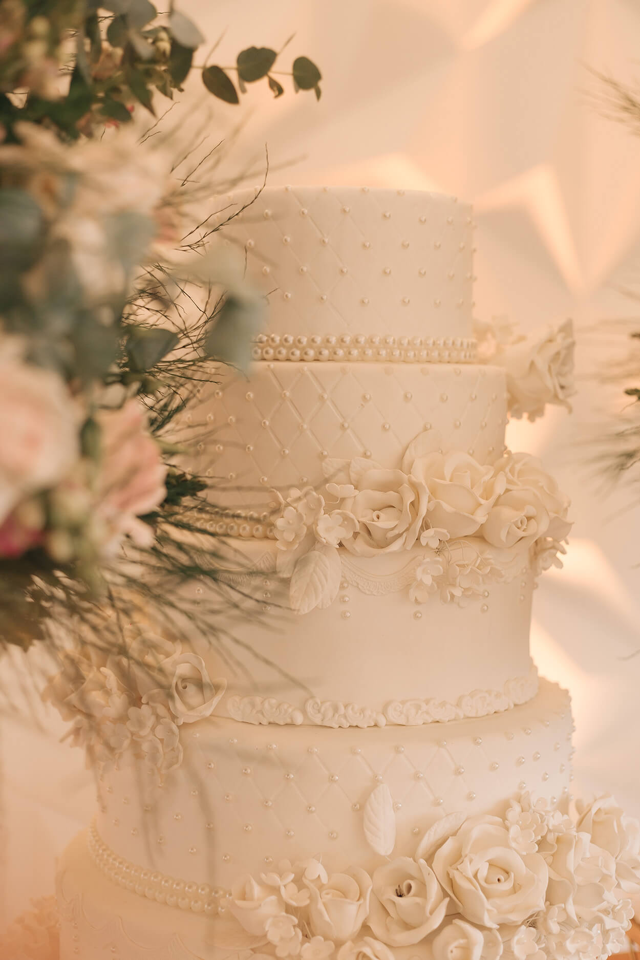 bolo de casamento branco com 4 andares e com flores e aplicação de pérolas