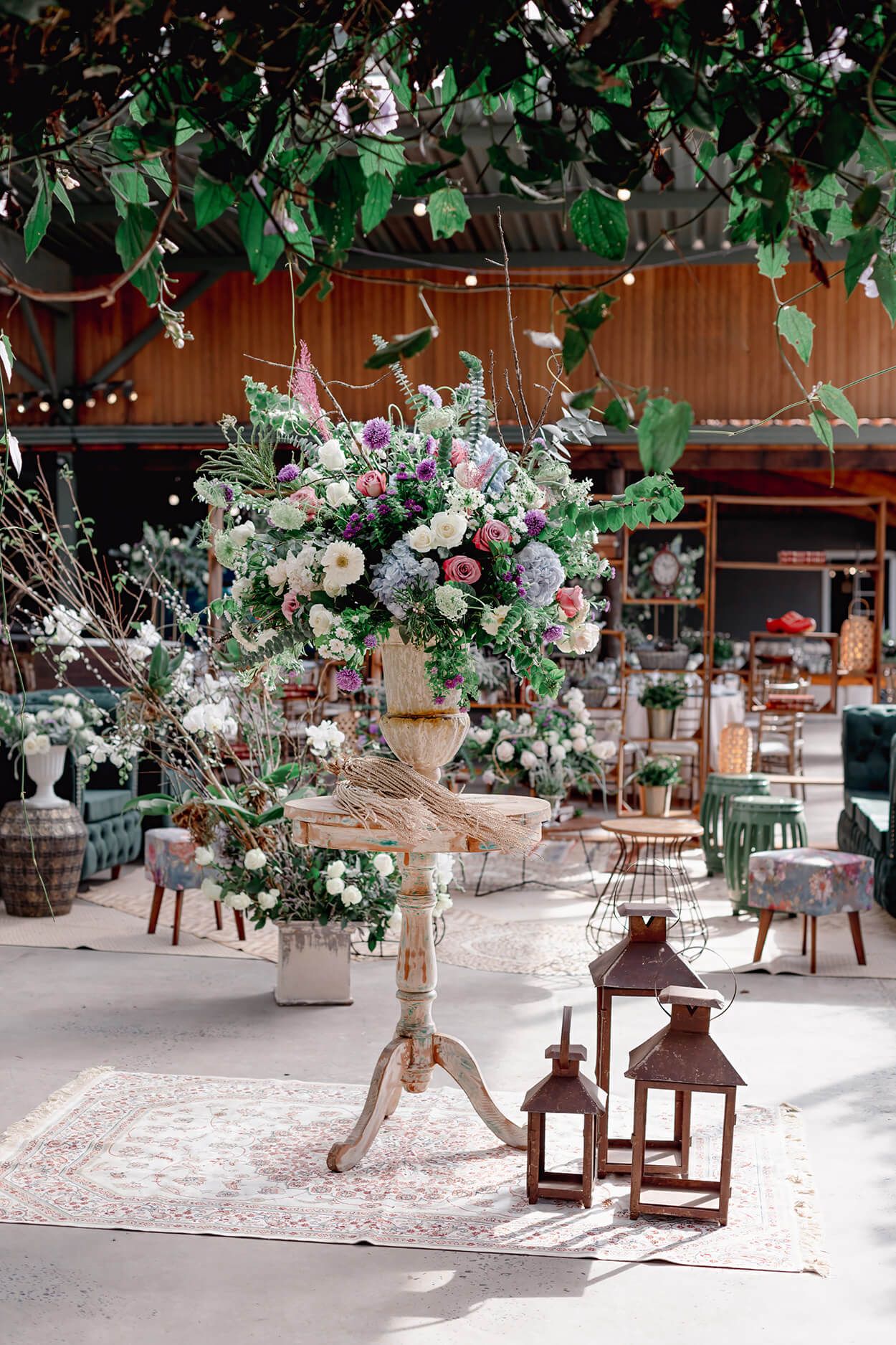 mesa de madeira redonda com vasos de flores azuis brancas rosas e lilás