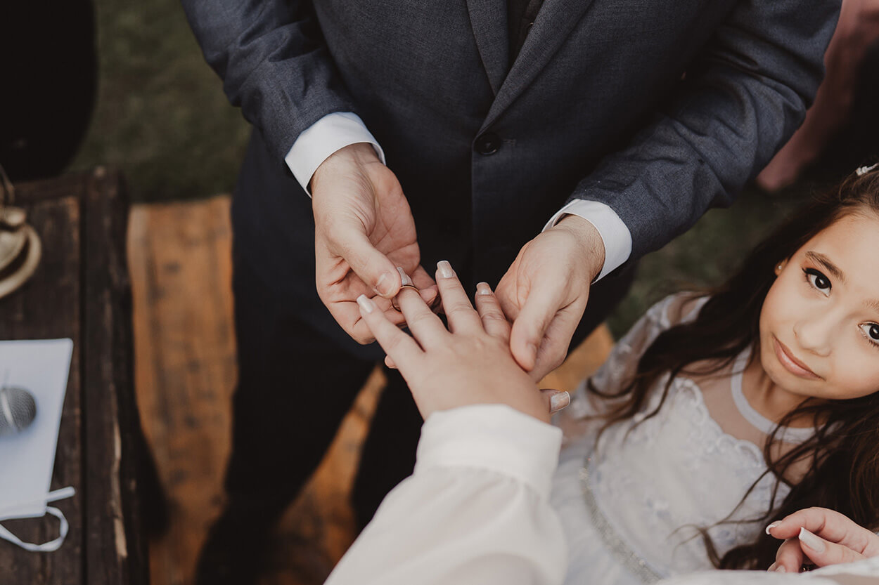homem colocando a aliança de casamento na mão da noiva