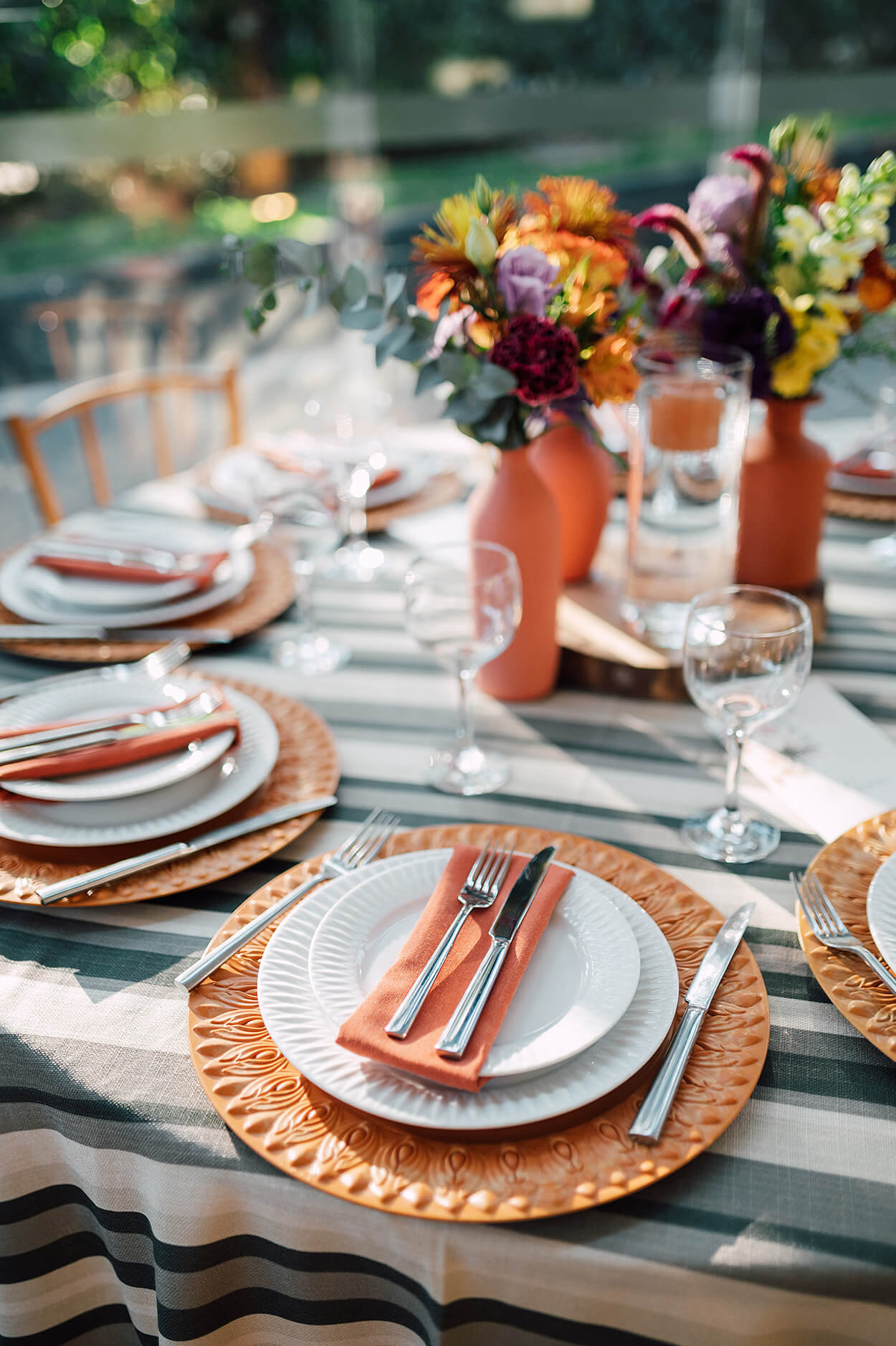 mesa posta com souplat e guardanapo laranja e arranjo com flores no centro