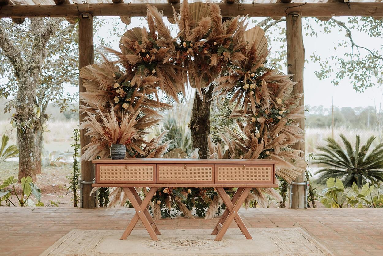 Altar com mesa de madeira e arco com flores terracota e capim dos pampas