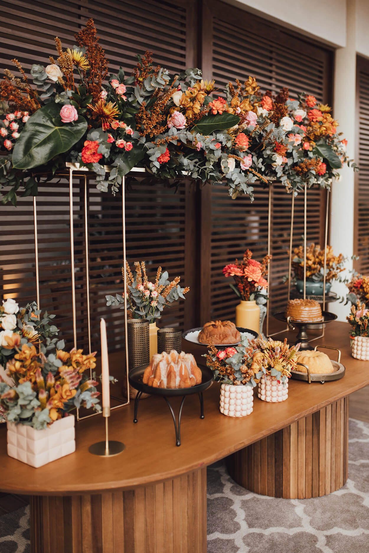 mesa de madeira moderna com cantos arredondados e vaos de flores velas e arranjos florais suspensos