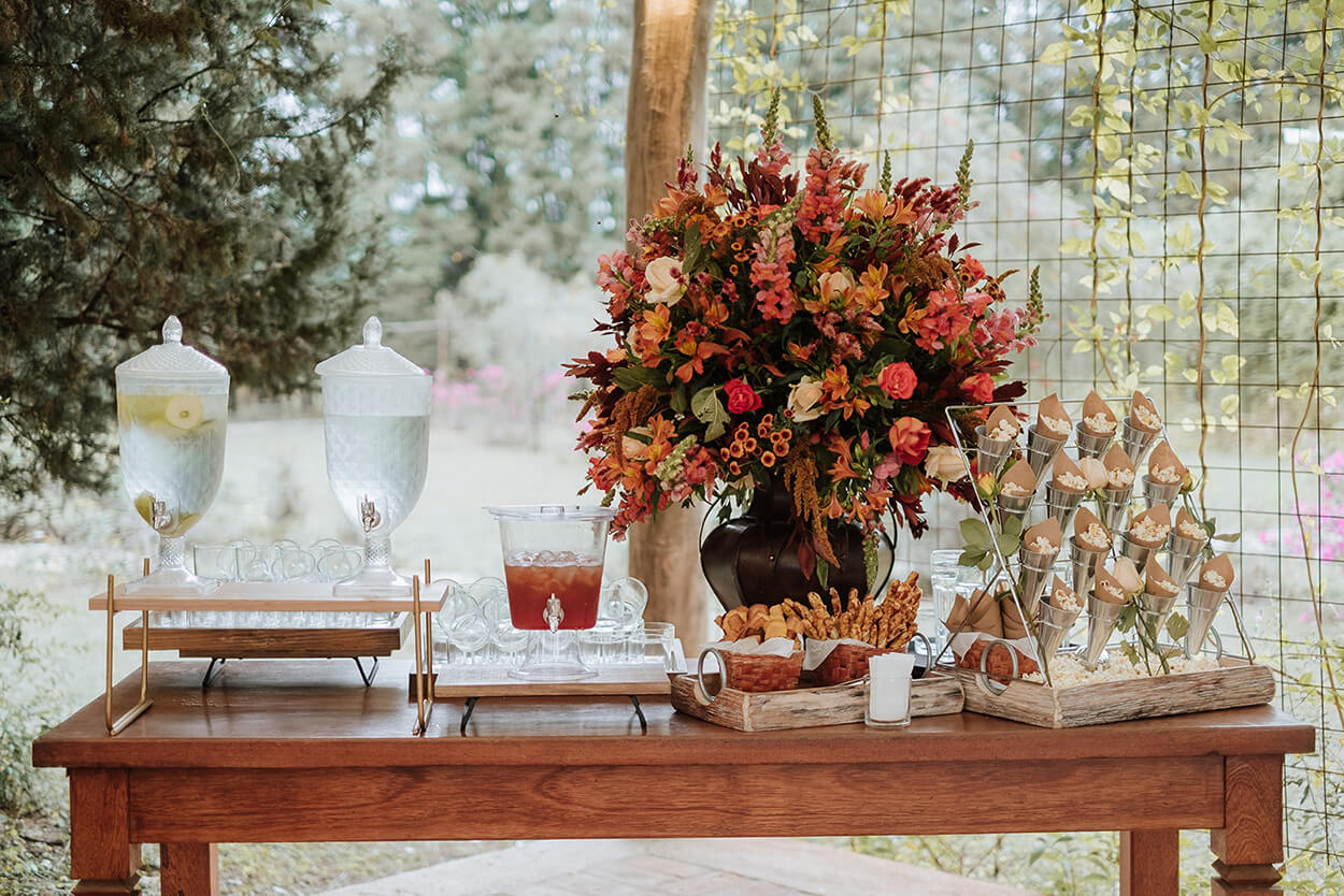 mesa de madeira com duas suqueiras e vasos com flores terracota e painel com porta pipocas