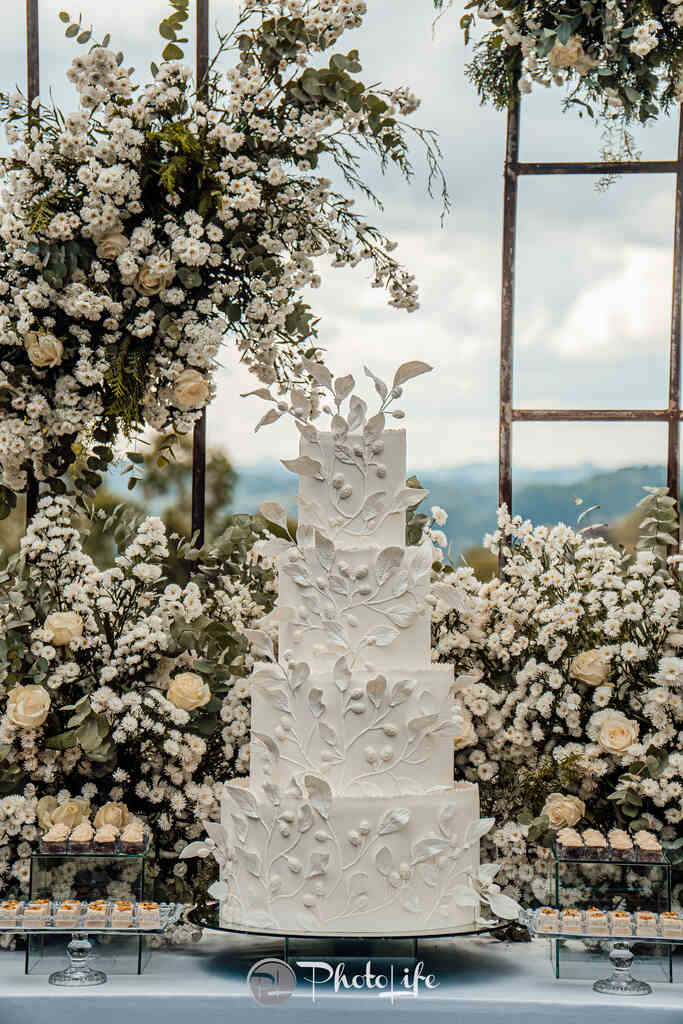 bolo de casamenot branco com quatro andares e aplicação de flores e folhas