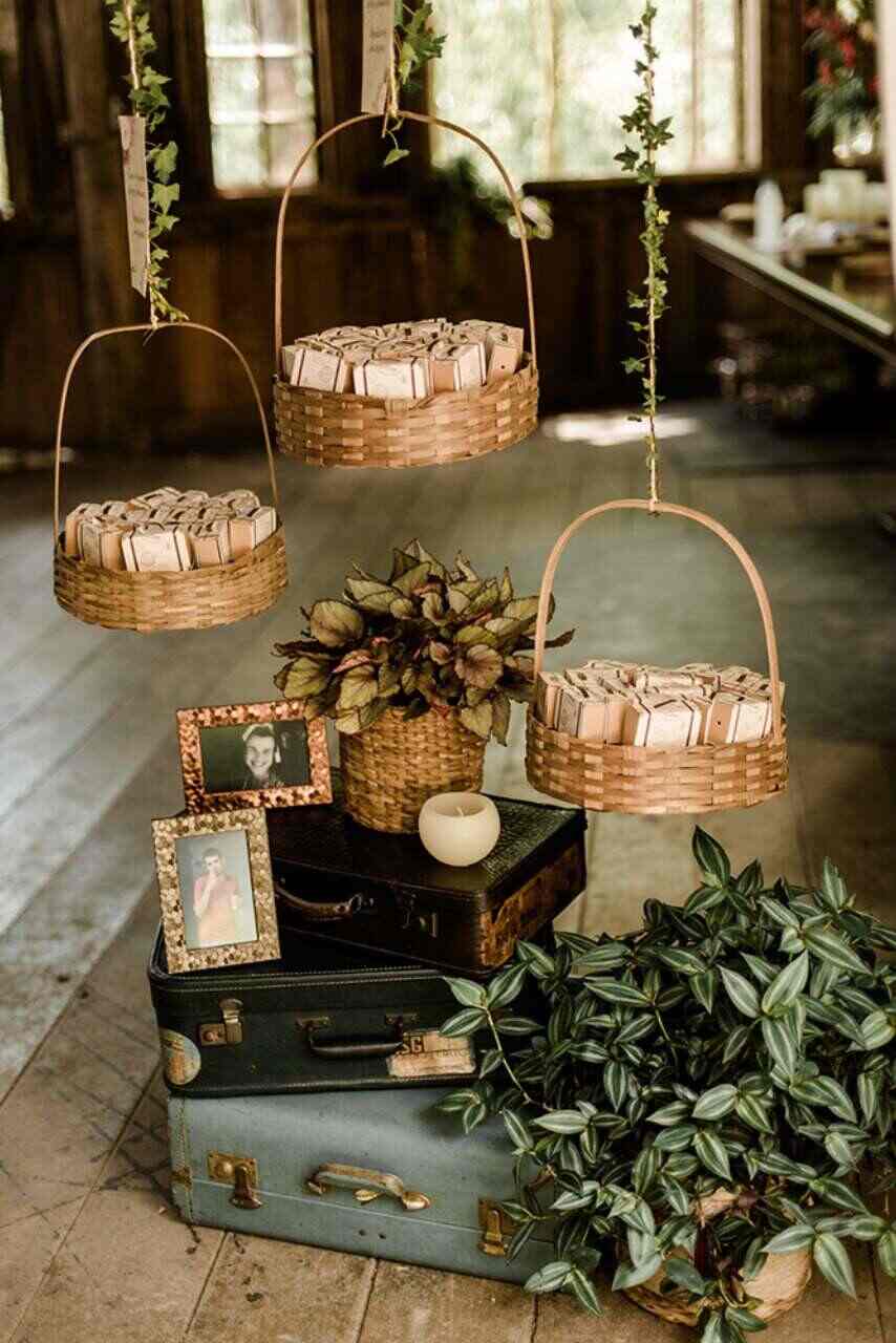 cestas de palha redondas suspensas por cordas com pacotes brancos e malas retrôs no chão com vasos de plantas e porta-retratos