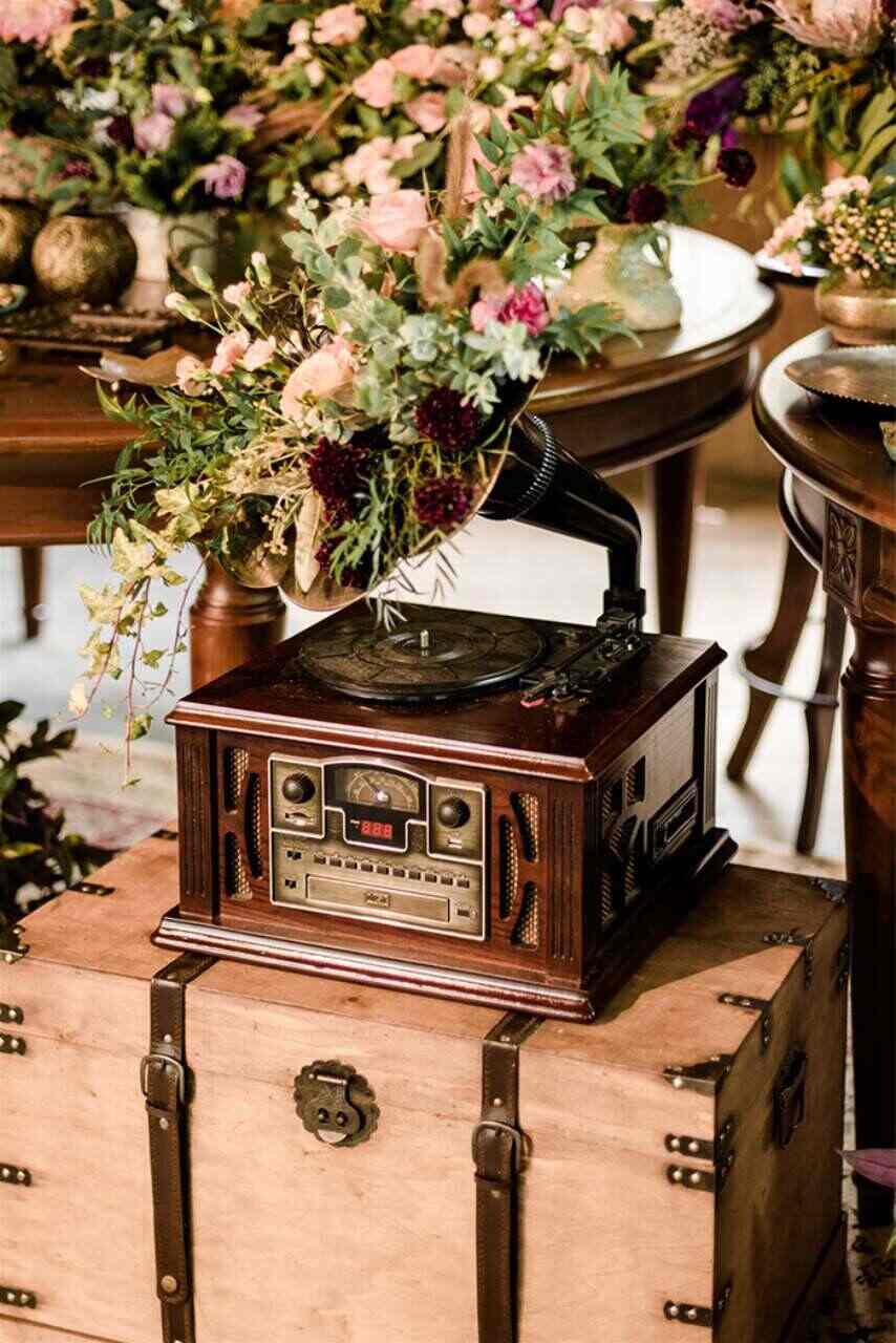 baú de madeira com cinto de couro e rádio antigo com flores coloridas por cima