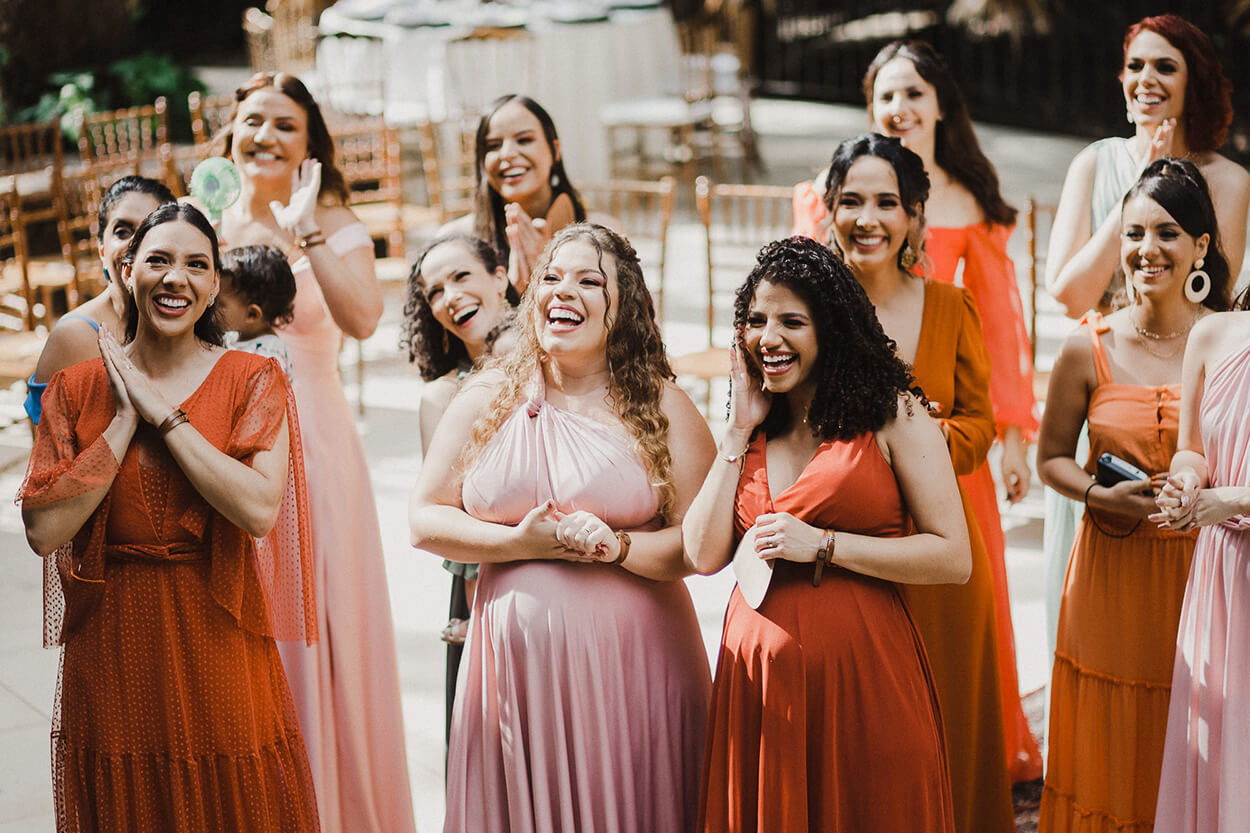 madrinhas com vestido terracota e rosa sorrindo quando viram a noiva no first look 