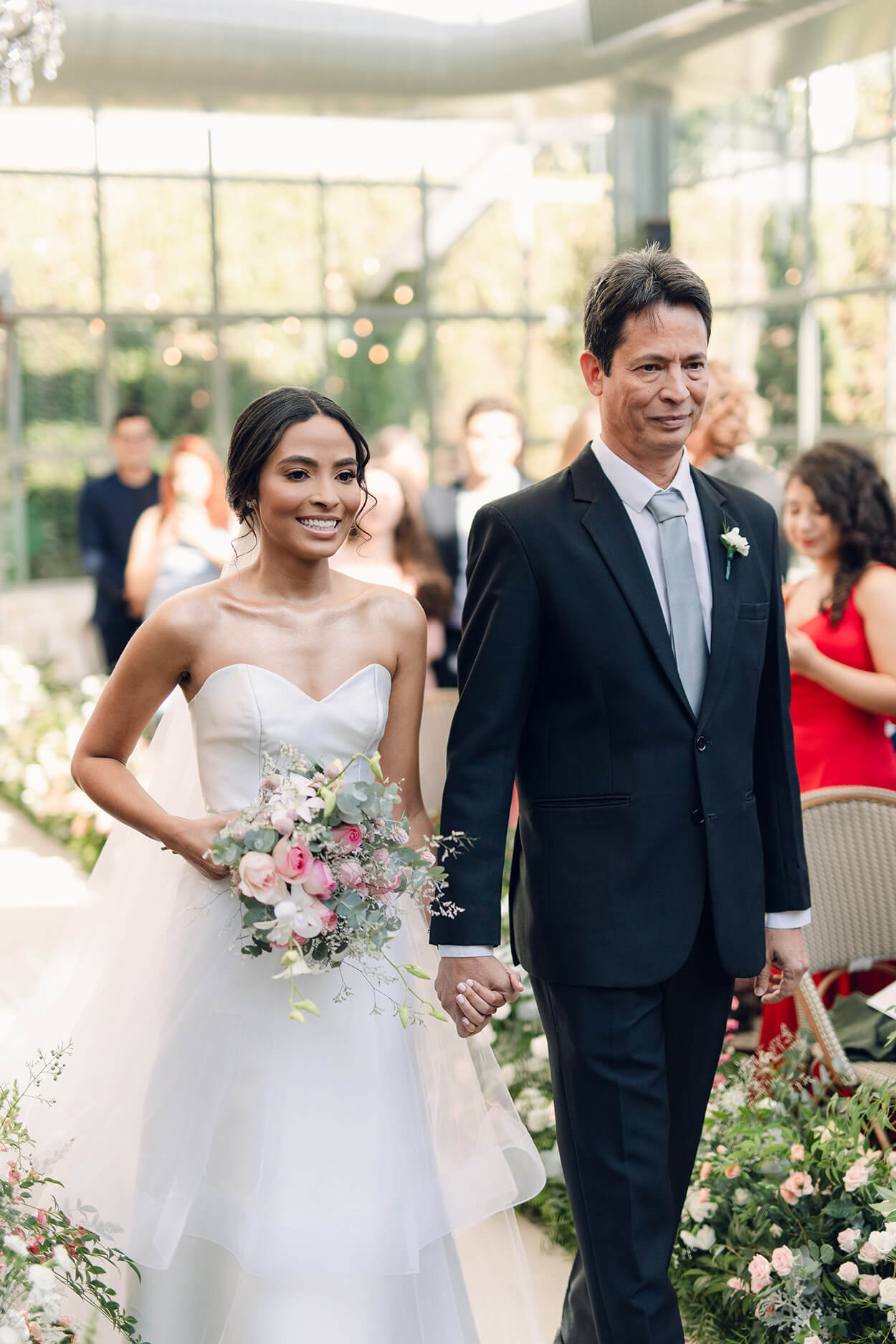 entrada da noiva com buquê redondo com flores brancas e rosas ao lado do pai com terno preto no salão