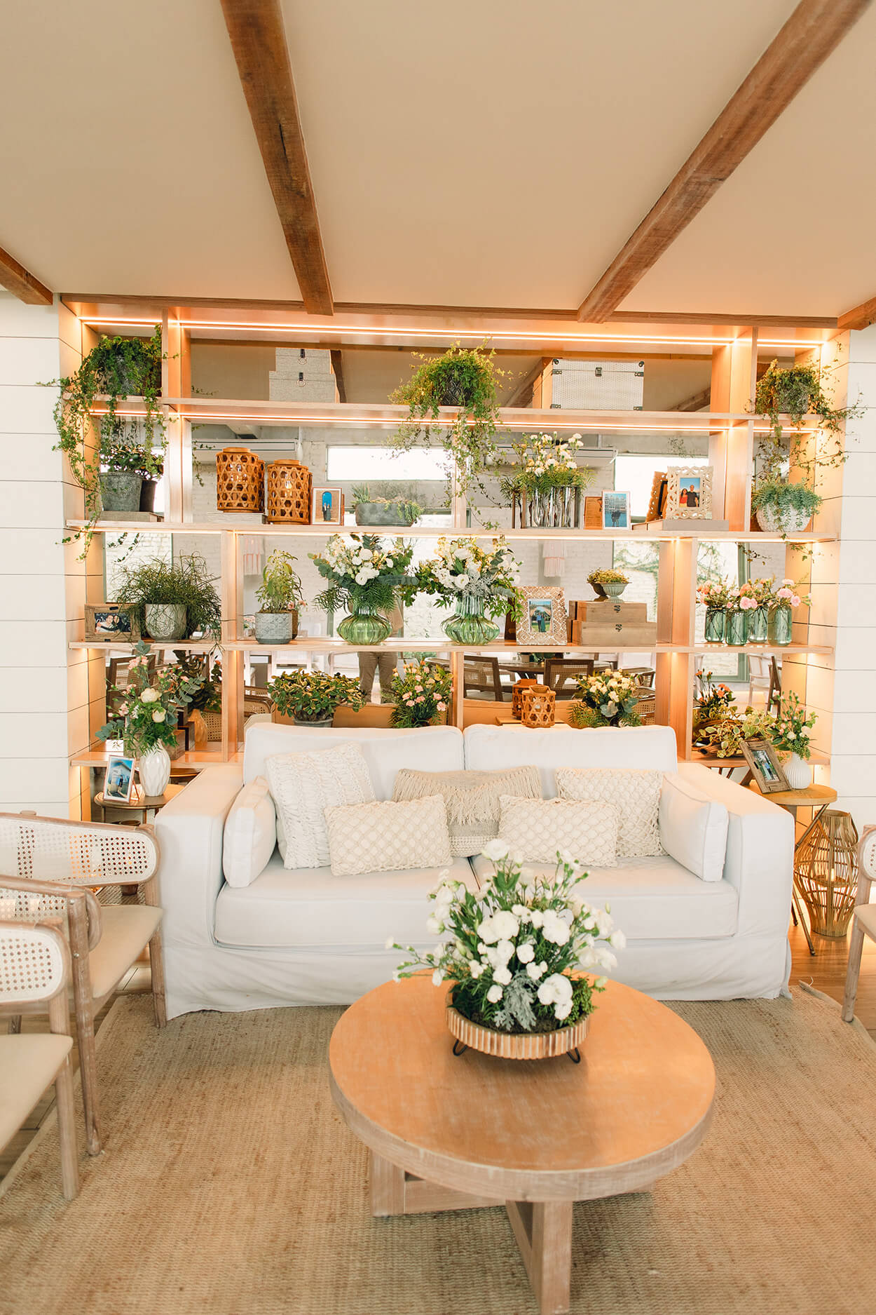 lounge com sofá branco e atrás com armário com vasos de plantas