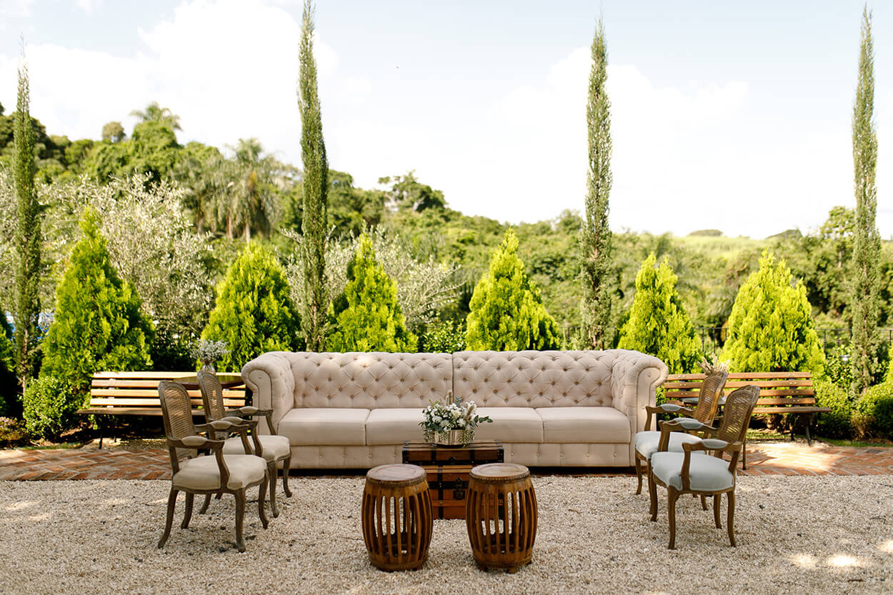 lounge ao ar livre com sofá clássico off white e cadeiras antigas 