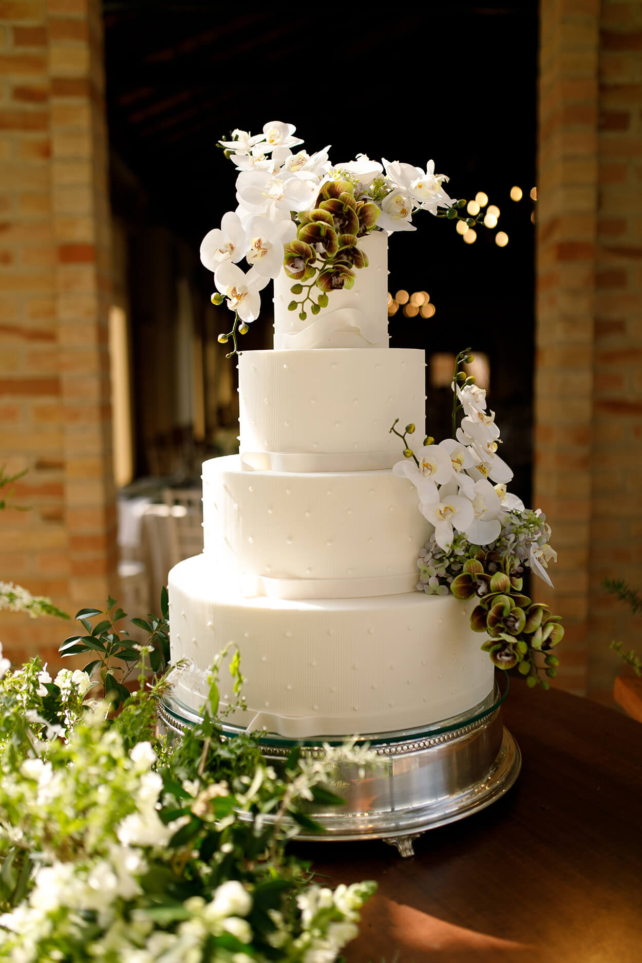 bolo de casamento com quatro andares brancos com aplicaçãod e mini pérolas e topo com orquídeas brancas e verdes