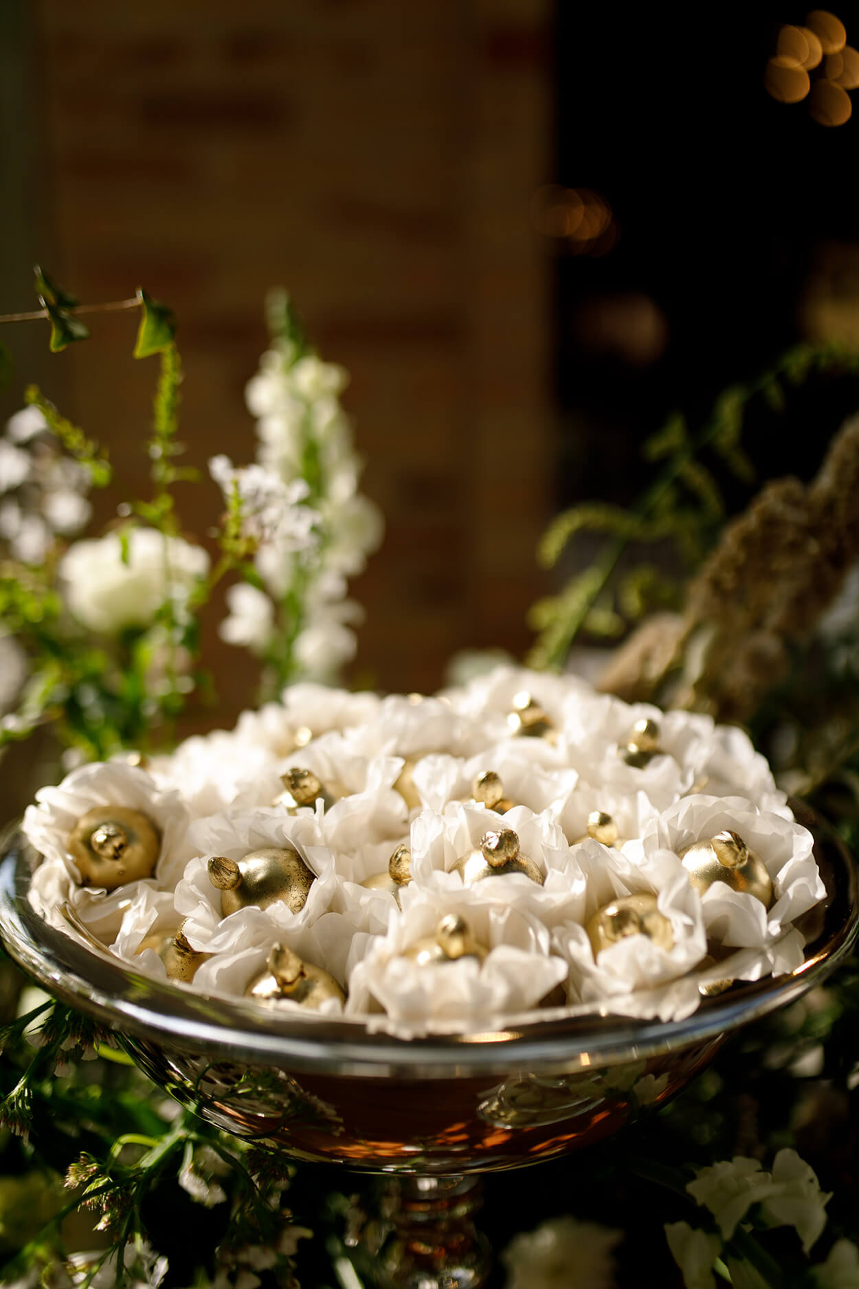 bandeja prata com doces dourados em embalagem de flor branca