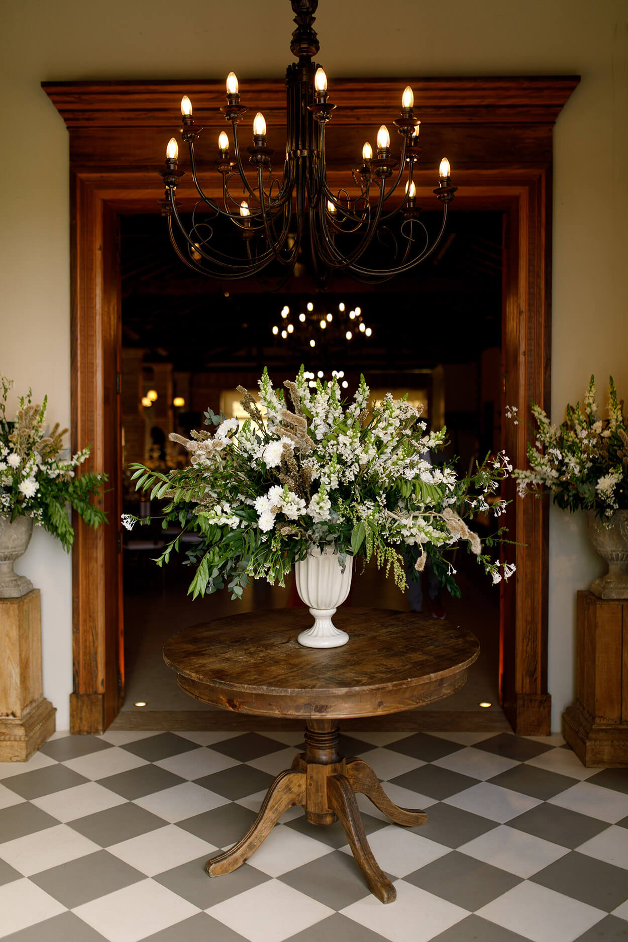 mesa redonda de madeira com vaso branco com arrajo foral grande com flores brancas