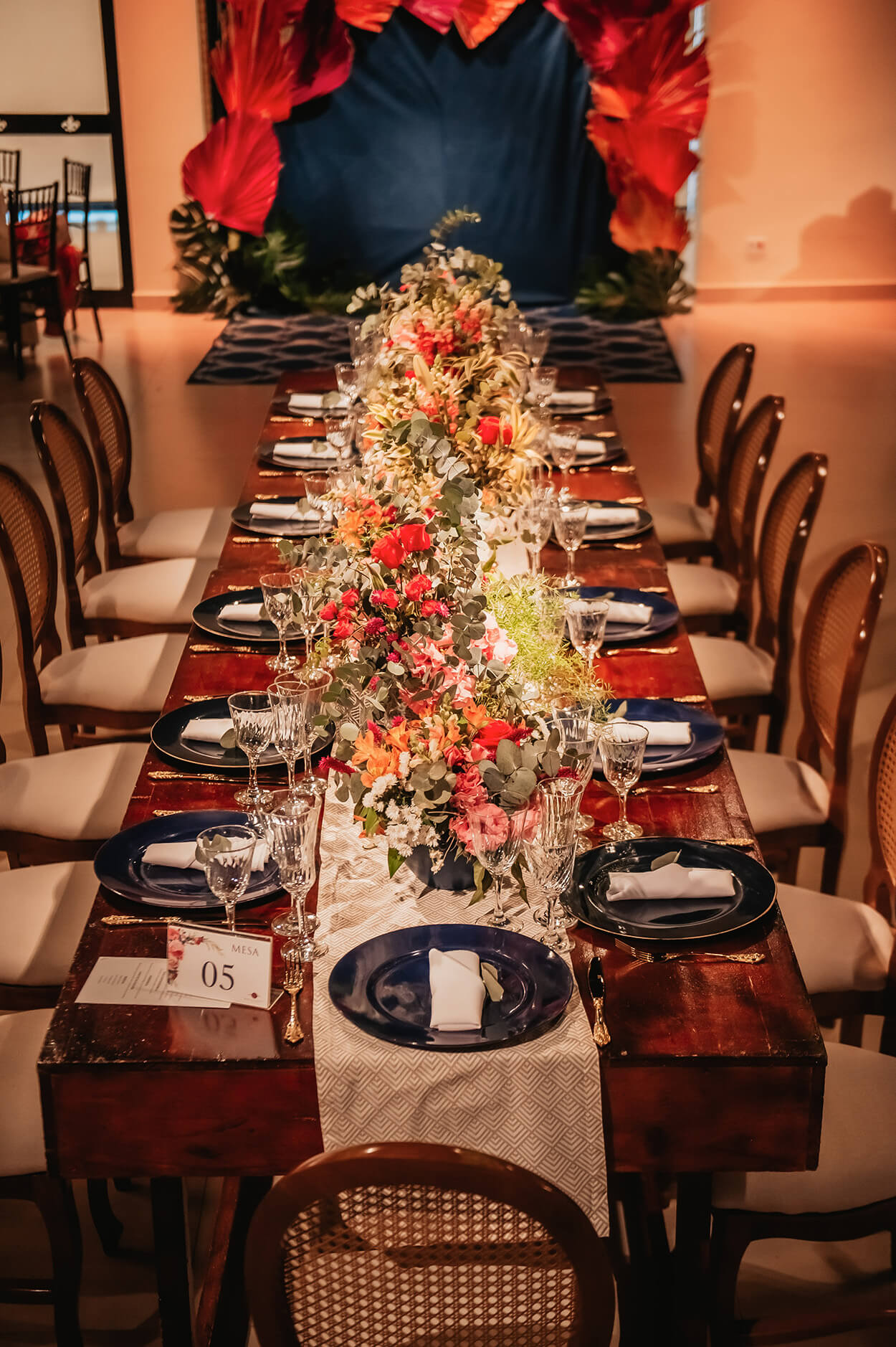 mesa posta com pratos azuis e flores coloridas no centro