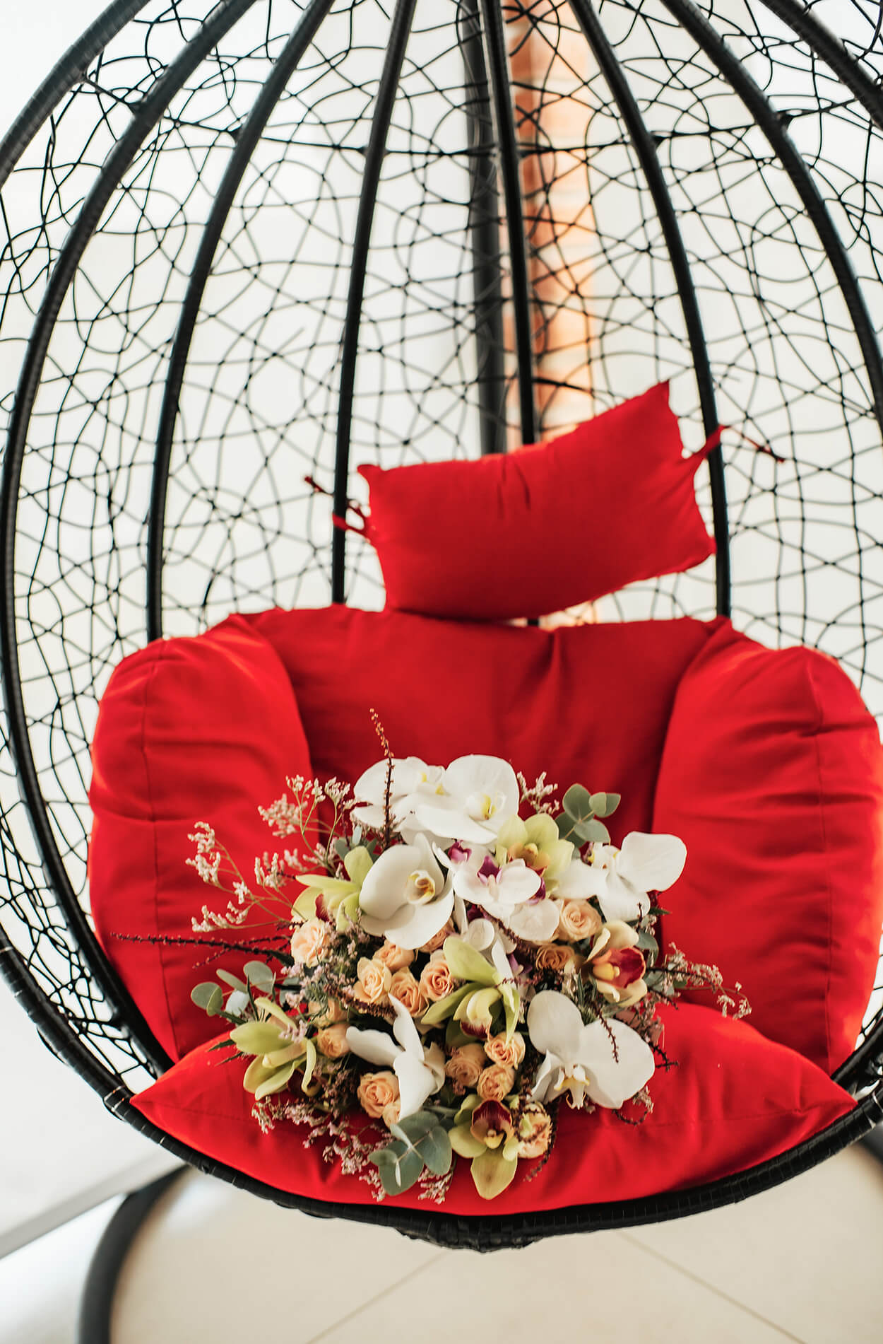 buquê com orquideas e flores coloridas em cima de poltrona vermelha