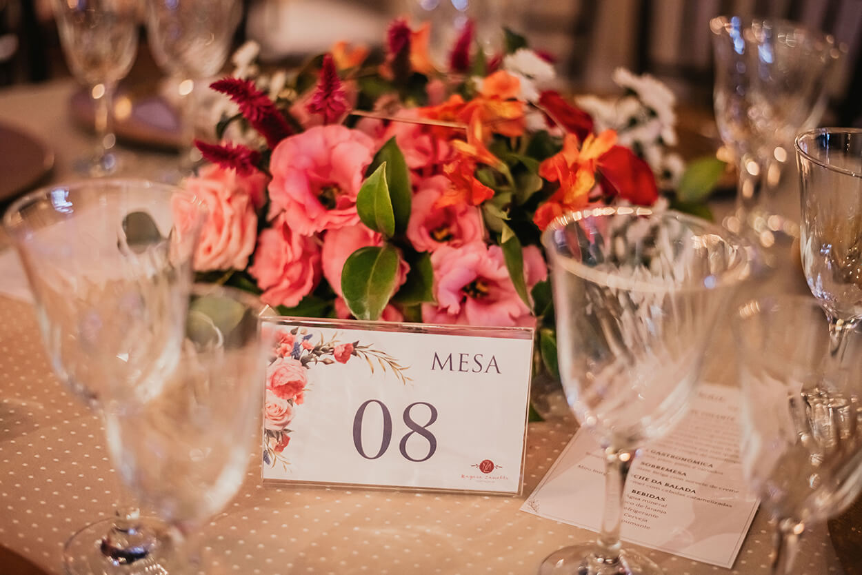 marcador de mesa e flores rosas e laranjas no centro da mesa