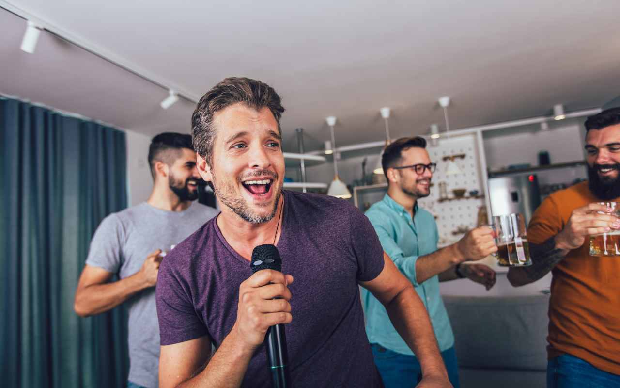 homem cantando com microfone na mão em festa de despedida de solteiro com karaokê com os amigos