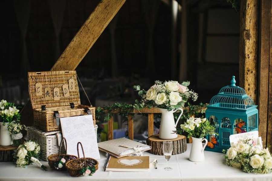 mesa para recados com gaiolas e cesto em volta tem um bule com flores brancas